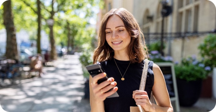 Woman smiling and standing outdoors on her phone