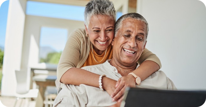 Mature couple smiling at home on a computer