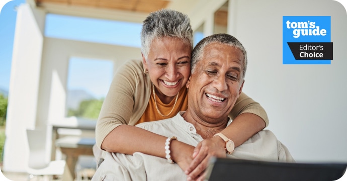 Mature couple smiling at home on a computer
