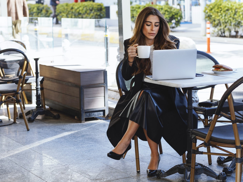 A woman looking concerned while holding a laptop, emphasizing the importance of protecting personal information in public.