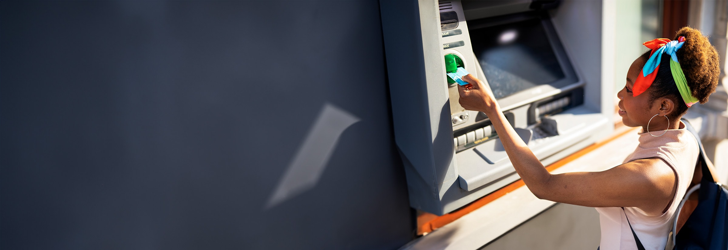 A man checking for a credit card skimmer while using an ATM.