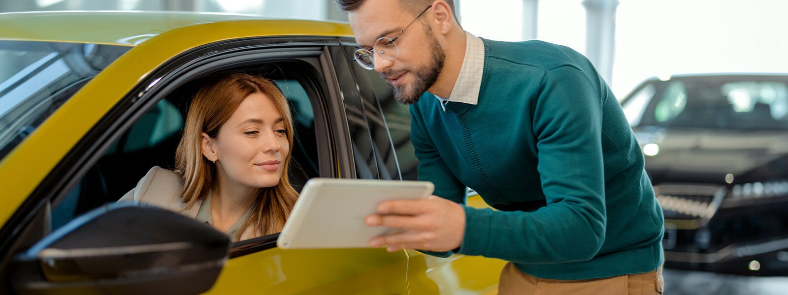 A car salesman helps a woman buy a car.