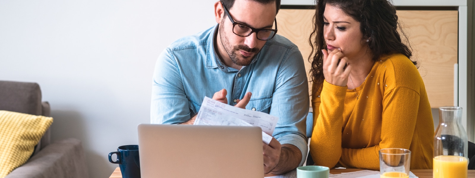 A couple reviews their statements to assess the damages of a recent bank scam.