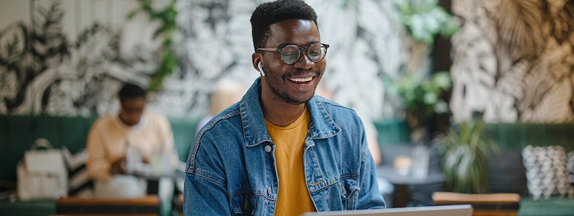 An image of a person at a coffee shop with a cup of coffee and a laptop.