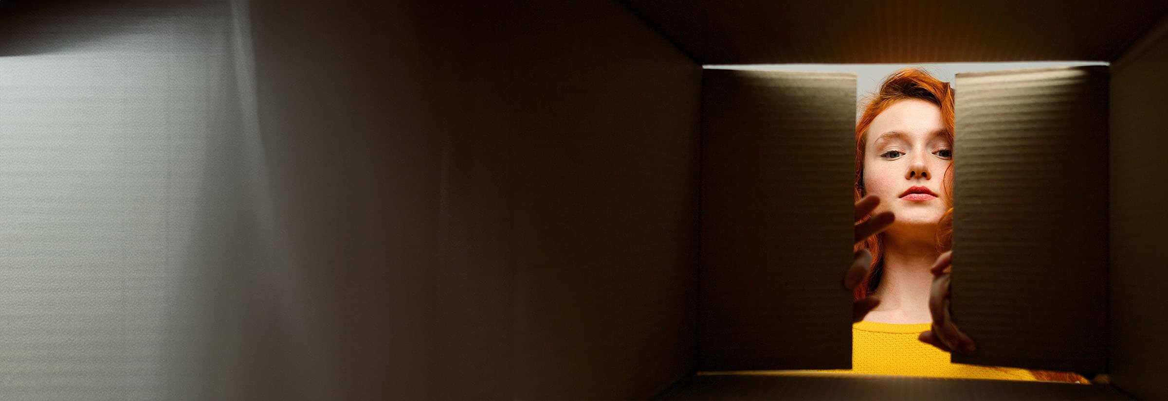 A woman peering into a box to see a fake product she’s received after being scammed on eBay.