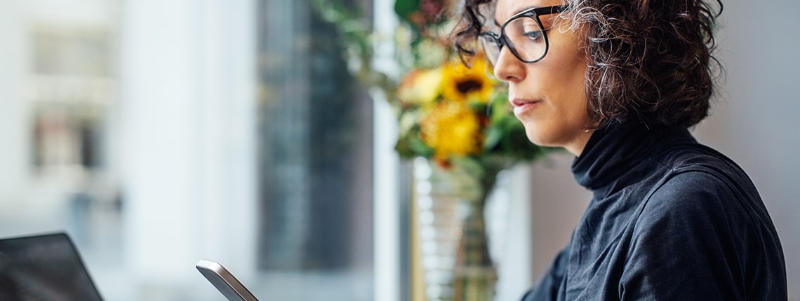 Image of a woman sitting at a desk with a laptop and phone