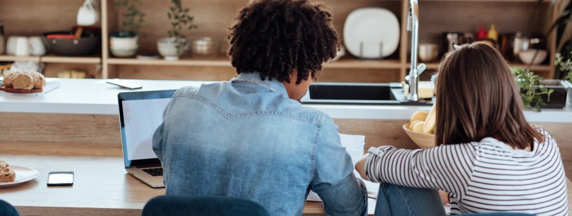 Two young people look at their tax records on a laptop.