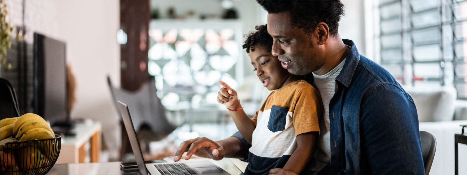 A man and his son using the computer to check if someone is using his identity.