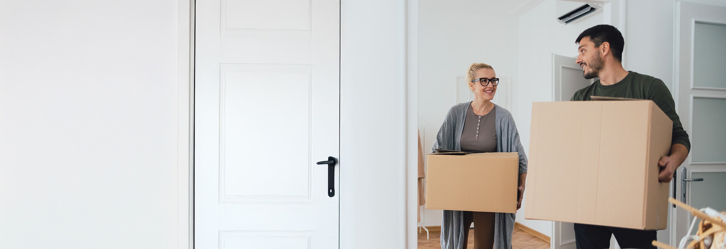 A couple moving boxes into their new apartment.