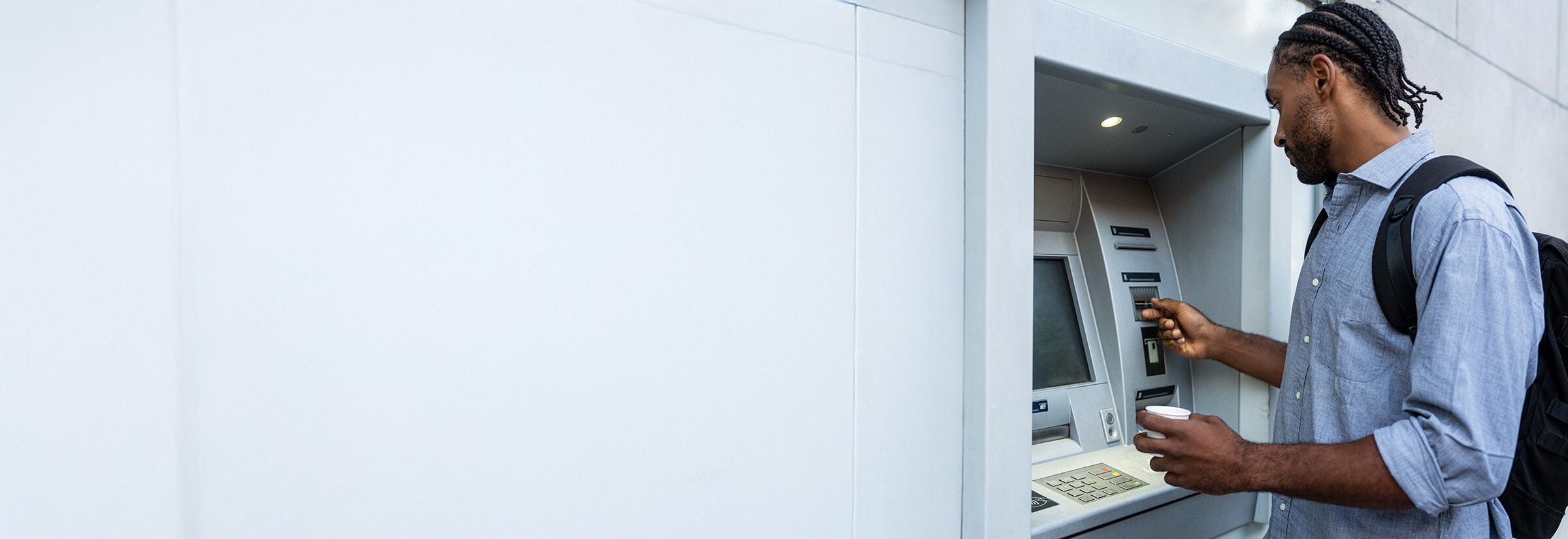 A man uses an ATM safely after checking for an ATM skimmer.