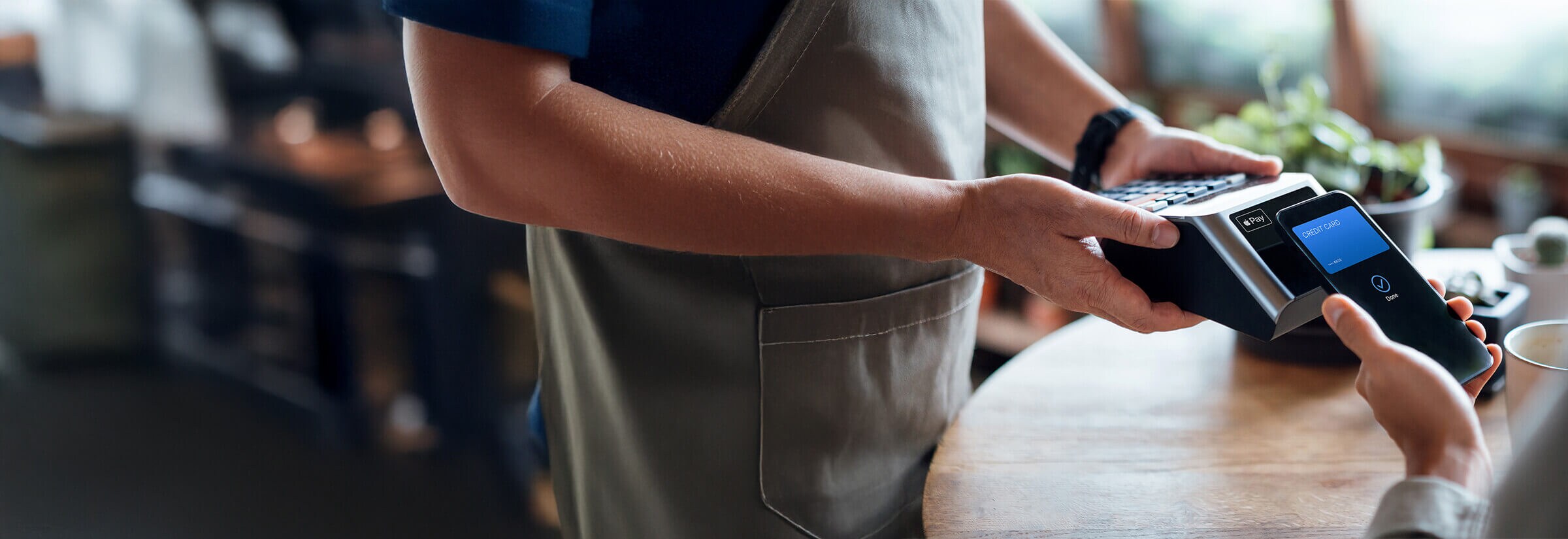 Person using Apple Pay to make a payment at a coffee shop.