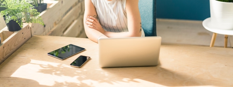 Person sitting at a desk looking at three screens – laptop, mobile phone, and tablet.