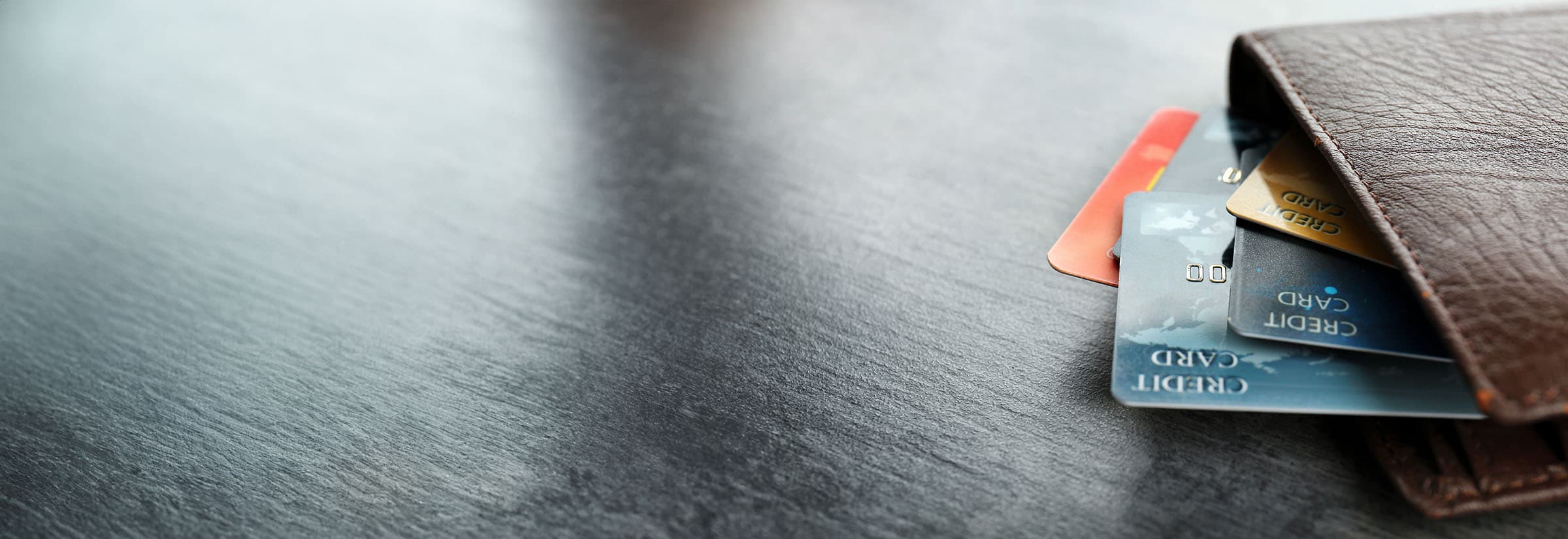 Multiple credit cards poking out of a wallet on a table.