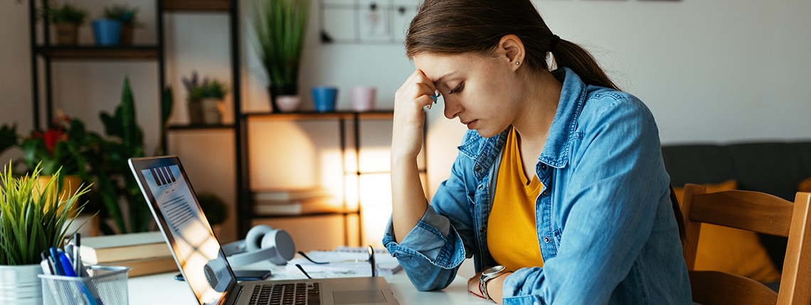 Woman sitting at a desk with a laptop researching the National Public Data breach.