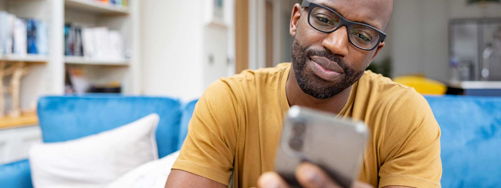 A man uses his smartphone to look at rental listings online, hopefully avoiding rental scams