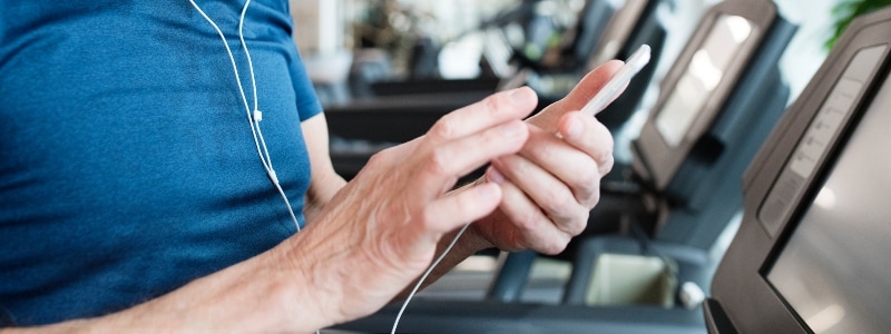 Close up on the hands of a man on a treadmill, learning about tax-related identity theft on social media.