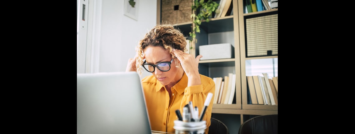 A person with glasses sitting at a desk with a laptop