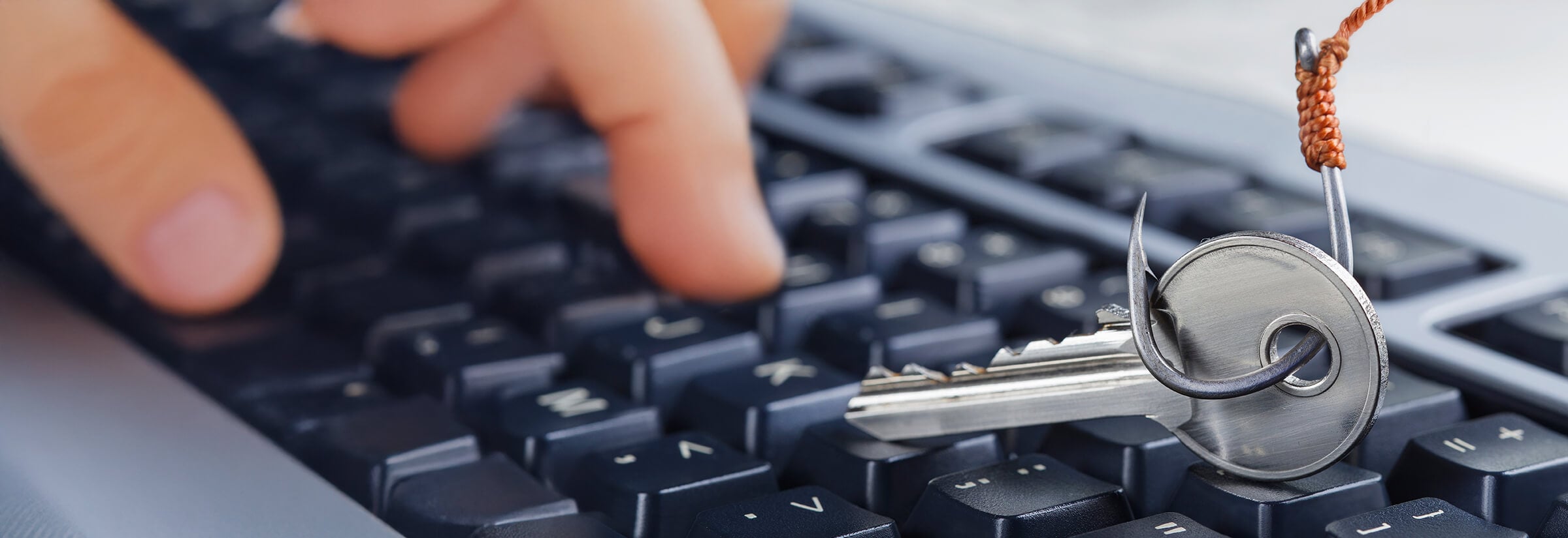 A fishing hook picking up a key off a keyboard, symbolizing a phishing attack.