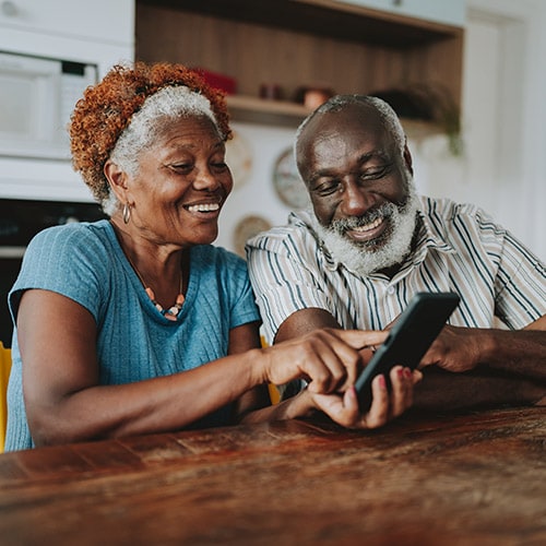 Elderly couple looking concerned as they read about the dangers of online scams targeting seniors.