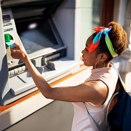 A man checking for a credit card skimmer while using an ATM.