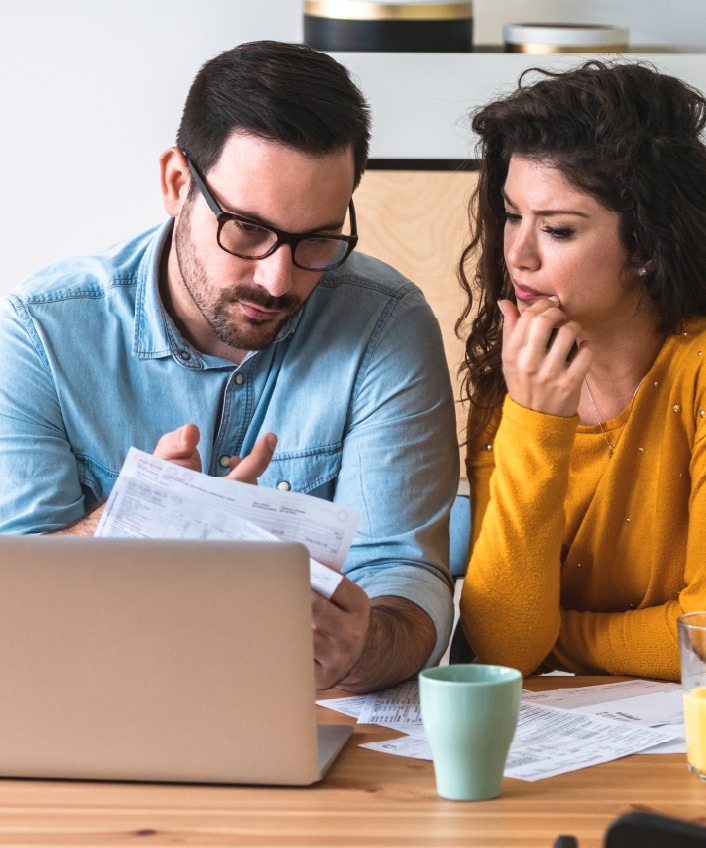 A couple reviews their statements to assess the damages of a recent bank scam.