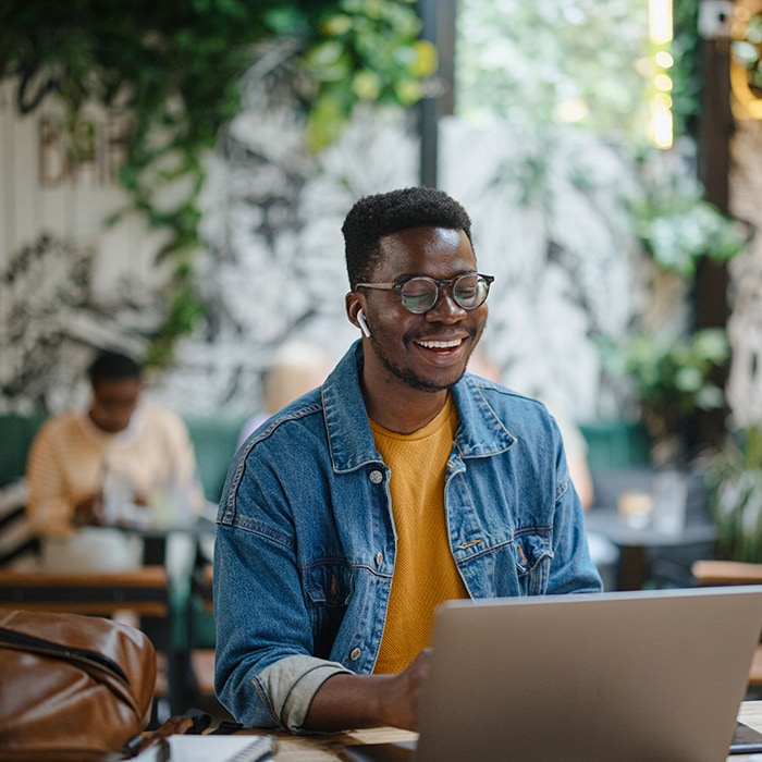 An image of a person at a coffee shop with a cup of coffee and a laptop.