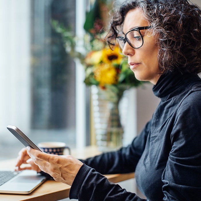 Image of a woman sitting at a desk with a laptop and phone