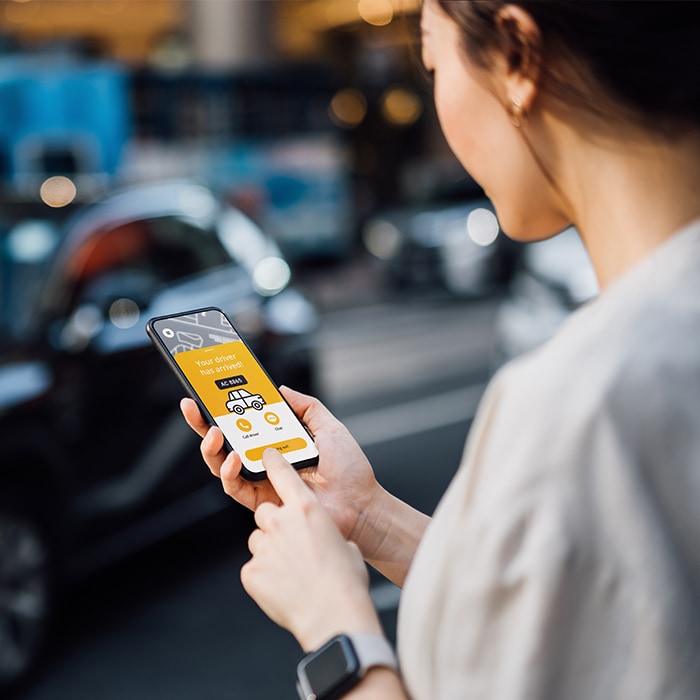 Image of a woman holding on a phone and standing on a street.