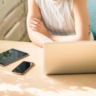 Person sitting at a desk looking at three screens – laptop, mobile phone, and tablet. 