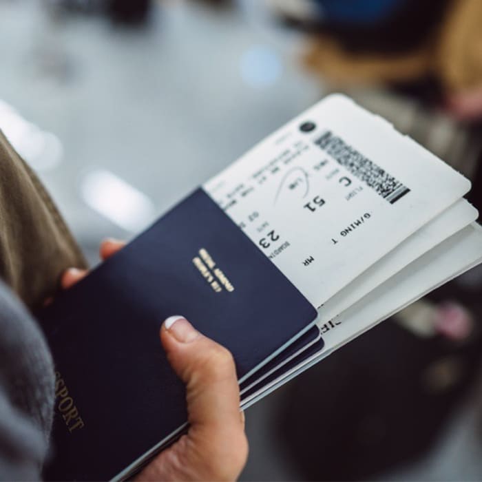 A person holding a passport and boarding pass.