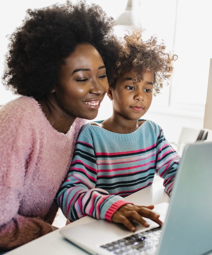 A woman and her child sit in front of a laptop computer, learning about Safer Internet Day together.