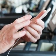 Close up on the hands of a man on a treadmill, learning about tax-related identity theft on social media.