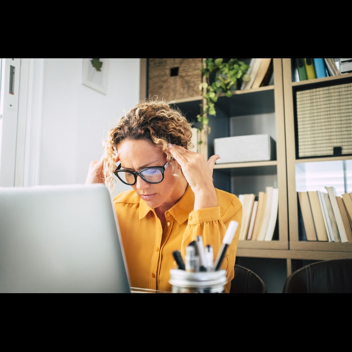 A person with glasses sitting at a desk with a laptop