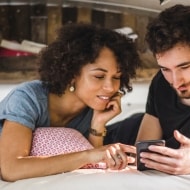 A couple lying down in van looks at a phone together.