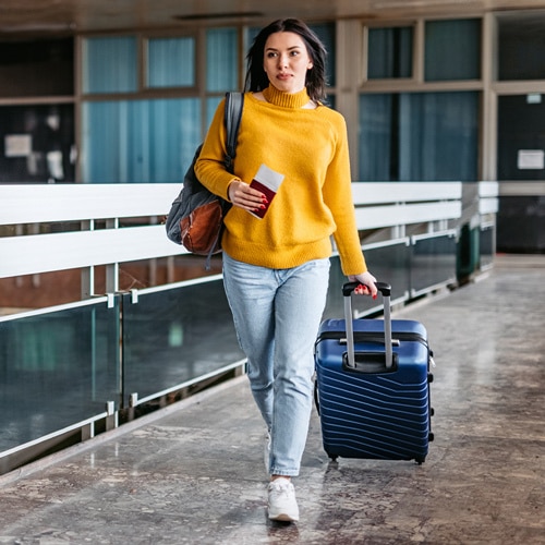 A woman walking through an airport with her passport in hand.